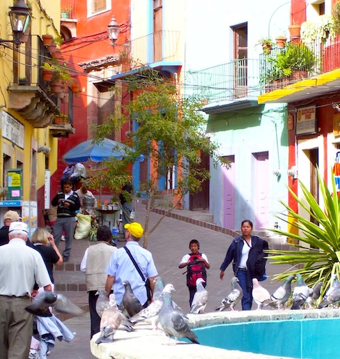angled entrance of alley in Guanajuato with people walking and pigeons