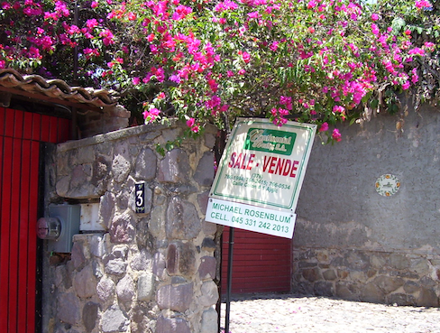 for sale sign, bougainvillea and rock wall