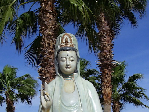 statue of quan yin with fan palms behind her