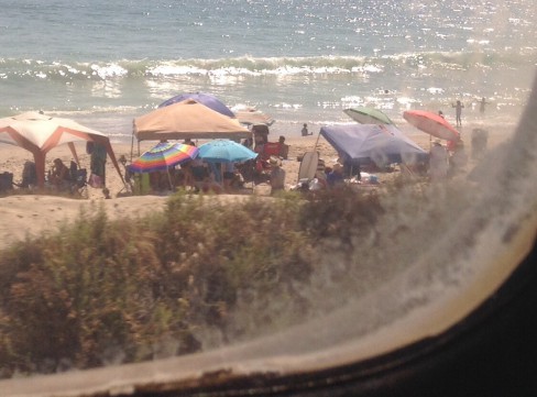 Colorful beach umbrellas north of Oceanside and small shining wave